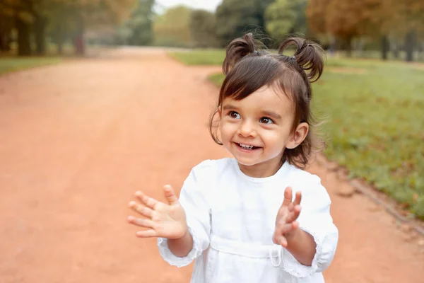 Маленькая счастливая кудрявая девочка хлопает в ладоши в парке — стоковое фото
