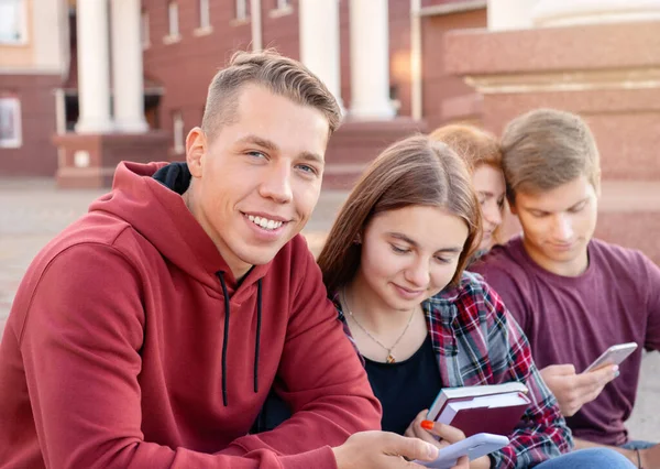 Szczęśliwy Uśmiechnięty Nastolatek Sprawdzający Telefon Grupą Studentów Schodach Pobliżu Uniwersytetu — Zdjęcie stockowe
