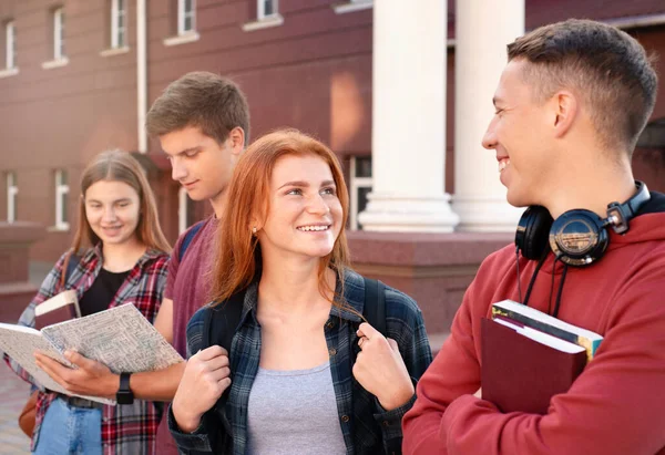 在大学的背景下 快乐地微笑着的青少年在另一个学生身边聊天 — 图库照片
