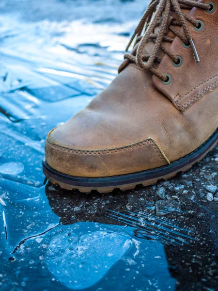 Close up of man\'s boots step on the icy surface of the ground.