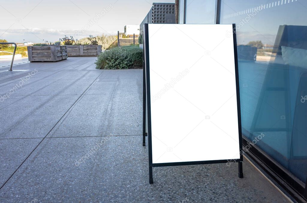 Blank white outdoor advertising stand/sandwich board mockup template. Clear street signage board placed on a pedestrian sidewalk.