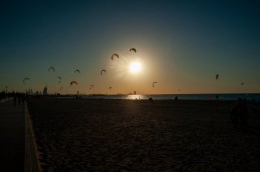 Sahilde gün batımında bir sürü uçurtma