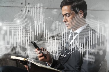 Ofisteki bir işadamı telefon ve stok grafiği kullanarak notlar alıyor. Çoklu maruz kalma. Resmi giysi.