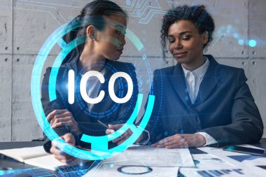 Modern ofiste iki iş kadını yeni projede birlikte çalışıyor. Çifte maruziyet. Başarı kavramı. ICO simgesi.