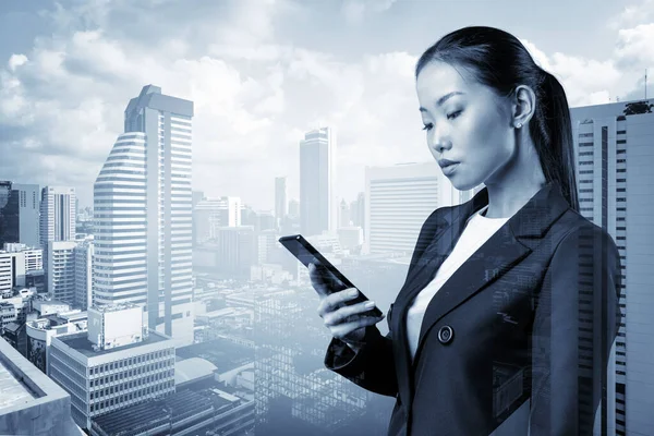 Процветающая молодая азиатская деловая женщина в костюме пишет по телефону детали корпоративной встречи. Бангкокский городской пейзаж. Концепция делового общения. Двойное воздействие. — стоковое фото