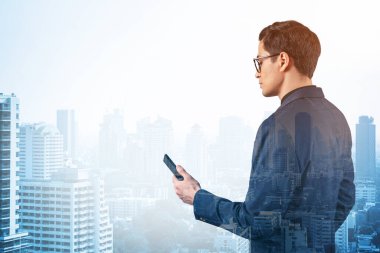 Takım elbiseli ve gözlüklü genç yakışıklı işadamı telefonla sorunu nasıl halledeceğini düşünüyor. Yeni kariyer fırsatları, işletme mastırı. Bangkok arka planda. Çift pozlama.