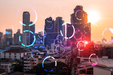 Soyut teknolojinin parlayan simgelerinin hologramı, günbatımında Bangkok 'un panoramik şehir manzarası, Asya. Dünyalar konsepti teknolojik değişiklikler. Çift pozlama.