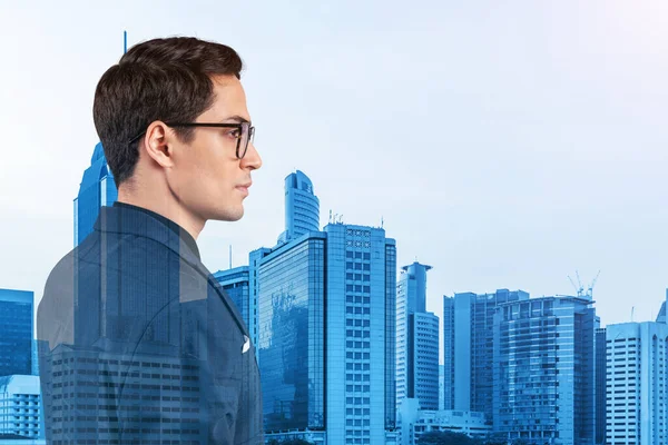 Joven hombre de negocios guapo en traje y gafas soñando con nuevas oportunidades de carrera después de la graduación del MBA. Kuala Lumpur en el fondo. Doble exposición. — Foto de Stock