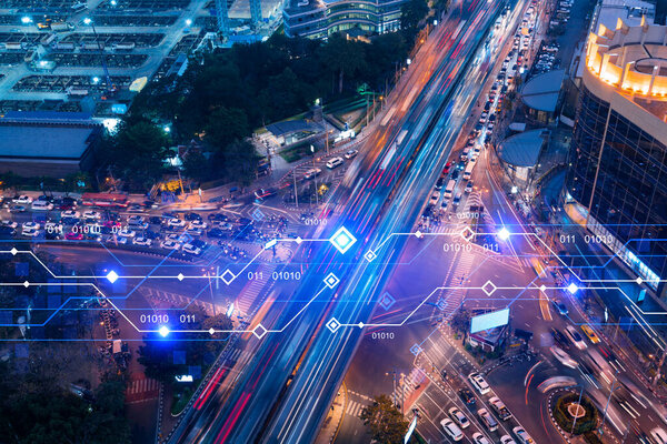 Technology hologram on aerial view of road, busy urban traffic highway at night. Junction network of transportation infrastructure. The concept of developing high-tech science in logistics.