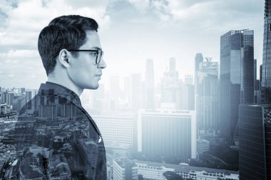 Takım elbiseli ve gözlüklü genç yakışıklı işadamı MBA mezuniyetinden sonra yeni kariyer fırsatları hayal ediyor. Singapur arka planda. Çift pozlama.