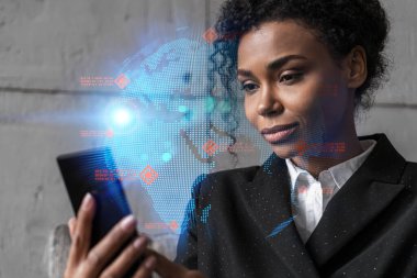 İş kadını telefonu kullanıyor, modern ofiste yeni bir proje üzerinde çalışıyor. Çifte maruziyet. Başarı kavramı. Dünya haritası Dünya hologramı.