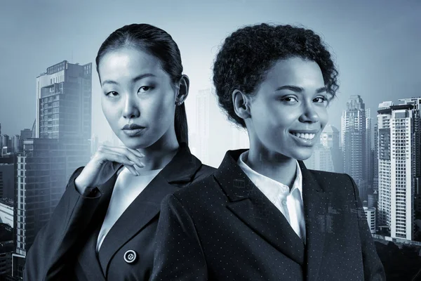 Две молодые привлекательные деловые женщины в костюмах мечтают о новых карьерных возможностях после окончания MBA. Концепция многонациональной корпоративной команды Бангкока на заднем плане. Двойное воздействие. — стоковое фото