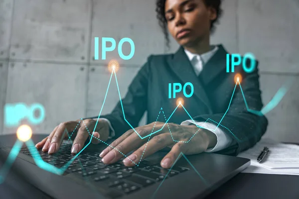 Geschäftsfrau tippt am Laptop in modernem Büro an neuem Projekt. Das IPO-Symbol zeichnet ein Hologramm. Doppelbelichtung. Erfolgskonzept. — Stockfoto
