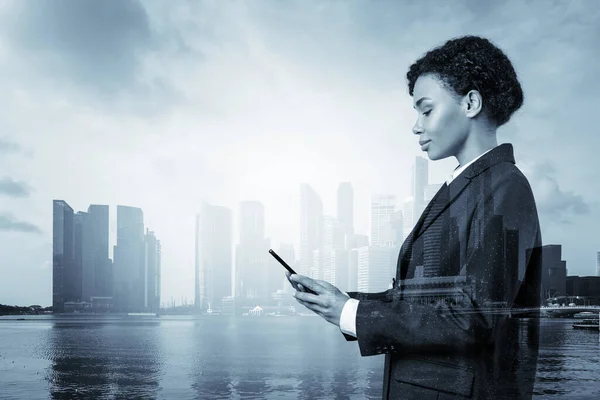 Attractive black African American business woman in suit using smart phone and thinking how to tackle the problem, new career opportunities, MBA. Singapore on background. Double exposure.
