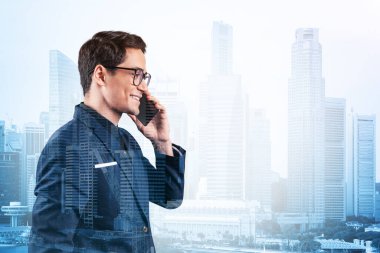 Takım elbiseli ve gözlüklü başarılı yakışıklı girişimci sürekli telefonla konuşuyor ve Singapur şehir manzarasına bakıyor. Sorun çözme danışmanlığı kavramı. Şehir merkezi manzarası. Çift pozlama.