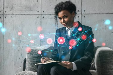 Yeni bir proje için modern ofiste dizüstü bilgisayarla yazı yazan bir iş kadını. Soyut teknoloji ikonu hologram çiziyor. Çifte maruziyet. Başarı kavramı.