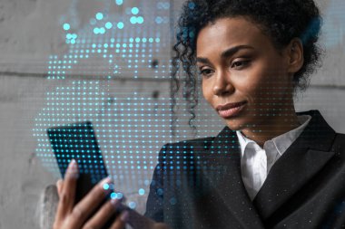 İş kadını telefonu kullanıyor, modern ofiste yeni bir proje üzerinde çalışıyor. Çifte maruziyet. Başarı kavramı. Dünya haritası Dünya hologramı.