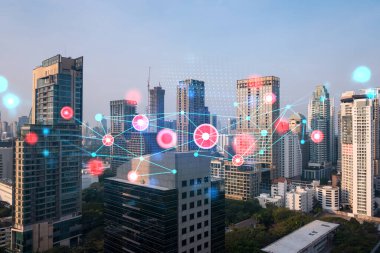 Soyut teknolojinin parlayan simgelerinin hologramı, günbatımında Bangkok 'un panoramik şehir manzarası, Asya. Dünyalar konsepti teknolojik değişiklikler. Çift pozlama.