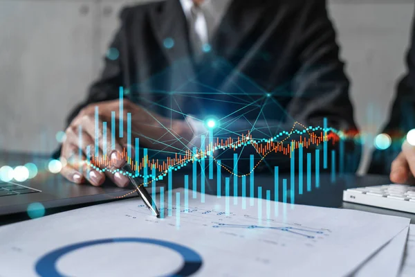 Two business people working together on stock market strategy. Try to analyze forex behavior. Financial graph hologram. Double exposure.