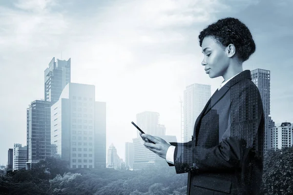 Attractive black African American business woman in suit using smart phone and thinking how to tackle the problem, new career opportunities, MBA. Bangkok on background. Double exposure.