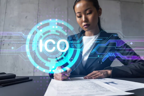 A woman signs contract and ico symbol hologram. Concept of initial coin offering. Multiexposure. International business.