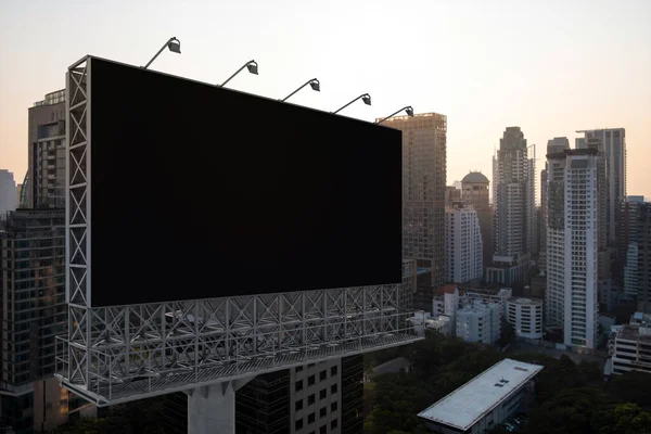 日落时分，曼谷城市景观背景的空白黑色道路广告牌。街头广告海报，模拟，3D渲染。侧视图。推广或推销观念的营销传播概念. — 图库照片