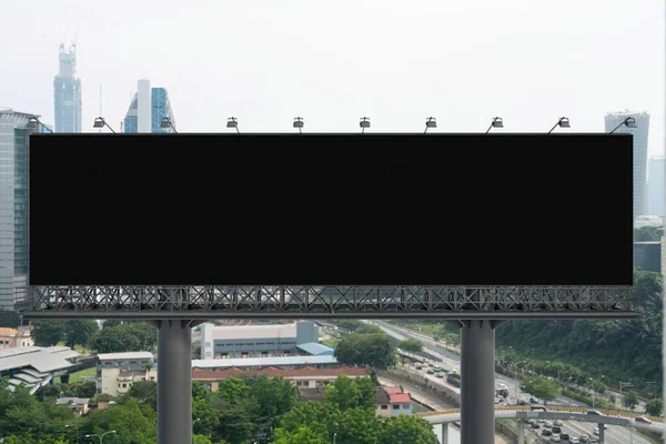 Blank black road billboard with Kuala Lumpur cityscape background at day time. Street advertising poster, mock up, 3D rendering. Front view. Concept of marketing to promote or sell services or ideas.