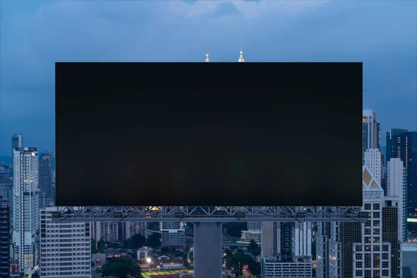 Panneau d'affichage de route noir blanc avec fond de paysage urbain Kuala Lumpur la nuit. Affiche publicitaire, maquette, rendu 3D. Vue de face. Concept de marketing pour promouvoir ou vendre une idée ou un produit. — Photo