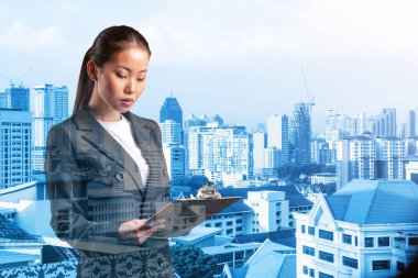 Takım elbiseli çekici Asyalı genç iş kadını not defterine not alıyor, yeni kariyer fırsatları, MBA ödevi. Kuala Lumpur arka planda. Çift pozlama.