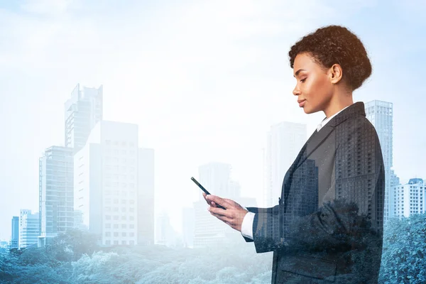 Attractive black African American business woman in suit using smart phone and thinking how to tackle the problem, new career opportunities, MBA. Bangkok on background. Double exposure.