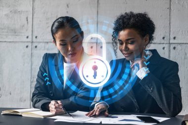 Modern ofiste iki iş kadını yeni projede birlikte çalışıyor. Çifte maruziyet. Başarı kavramı. Güvenlik kilidi simgesi.