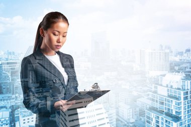 Takım elbiseli çekici Asyalı genç iş kadını not defterine not alıyor, yeni kariyer fırsatları, MBA ödevi. Bangkok arka planda. Çift pozlama.