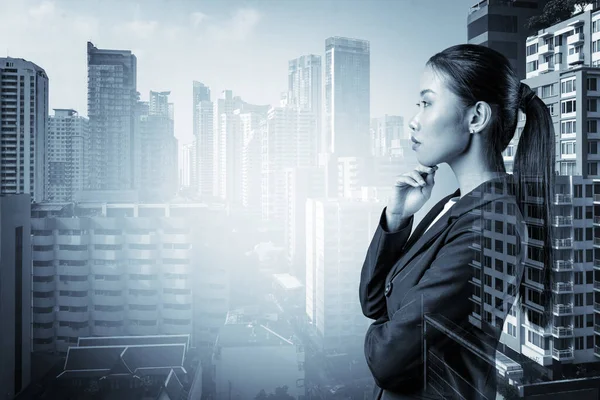 Atractiva joven mujer de negocios asiática en traje con la mano en la barbilla pensando cómo tener éxito, nuevas oportunidades de carrera, MBA. Bangkok en el fondo. Doble exposición. — Foto de Stock