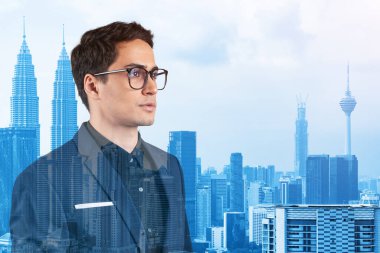 Takım elbiseli ve gözlüklü genç yakışıklı işadamı MBA mezuniyetinden sonra yeni kariyer fırsatları hayal ediyor. Kuala Lumpur arka planda. Çift pozlama.