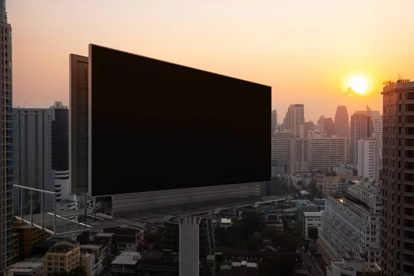 Leere schwarze Straßenwerbetafel mit Bangkoks Stadtbild bei Sonnenuntergang. Straßenwerbeplakat, Mock-up, 3D-Rendering. Seitenansicht. Das Konzept der Marketing-Kommunikation zur Förderung oder zum Verkauf von Ideen. — Stockfoto