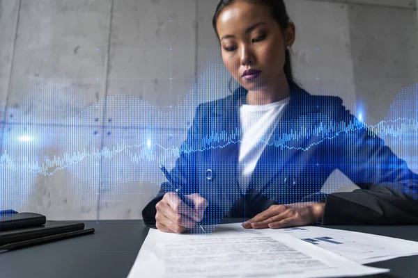 A woman signs contract and forex chart hologram. Concept of stock market analysis. Multiexposure. International business.