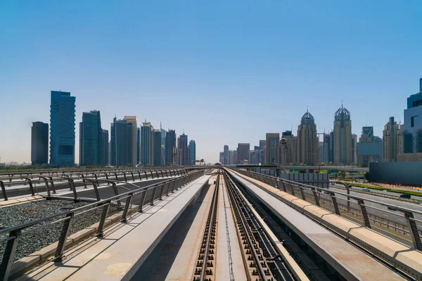 The way towards skyscrapers of financial downtown of Dubai by modern futuristic train. Tech railway delivers commuters to the financial downtown of Dubai. International business hub.