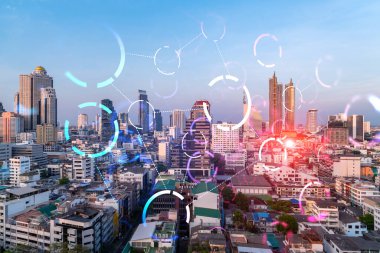 Soyut teknolojinin parlayan simgelerinin hologramı, günbatımında Bangkok 'un panoramik şehir manzarası, Asya. Dünyalar konsepti teknolojik değişiklikler. Çift pozlama.