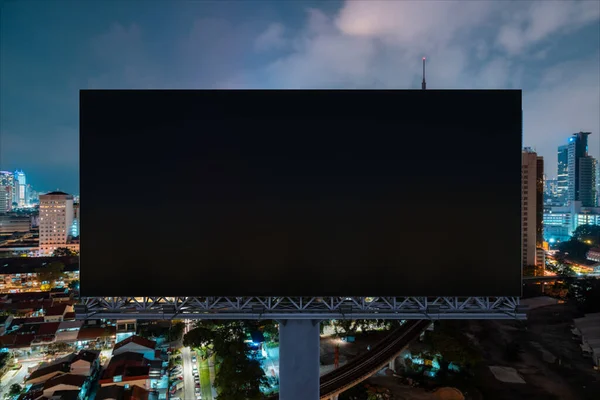 Panneau d'affichage de route noir blanc avec fond de paysage urbain Kuala Lumpur la nuit. Affiche publicitaire, maquette, rendu 3D. Vue de face. Concept de marketing pour promouvoir ou vendre une idée ou un produit. — Photo