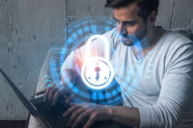 Ciddi bir Kafkasyalı programcı, verileri korumak için yeni bir güvenlik sistemi geliştirmek için dizüstü bilgisayar kullanıyor. Çifte maruziyet. IT hologram simgesini kilitle.