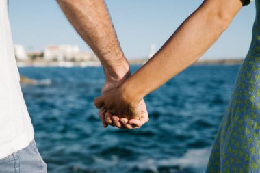 Çift el ele tutuşup denize bakıyor.