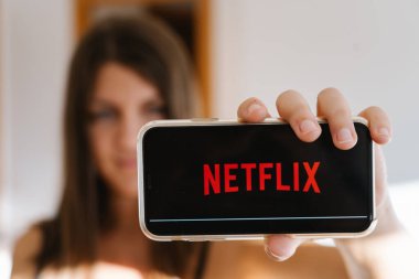 Netflix logosuyla cep telefonunun ekranını gösteren kız