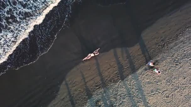 空中ビューの女の子は波の間で海のビーチの砂の上に横たわっている — ストック動画