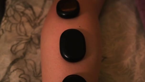 Massage stones on the girls leg under romantic light — Stock Video