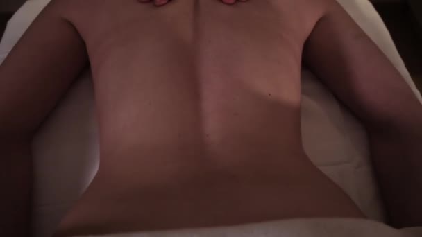 O massagista massageia as meninas de volta com as mãos sob luz romântica — Vídeo de Stock