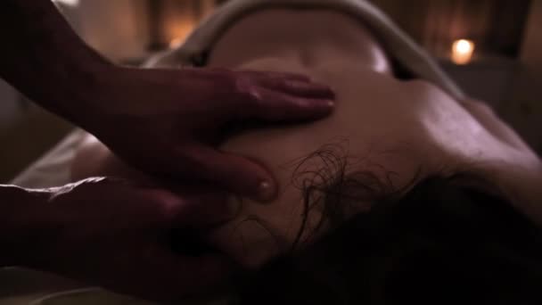 O massagista massageia o pescoço do ombro das meninas com as mãos sob luz romântica — Vídeo de Stock