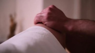 Masör, romantik ışık altında kızların bacaklarına masaj yapar.