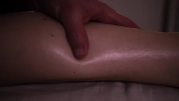 The masseur massages the girls leg with hands under romantic light — Stock Video