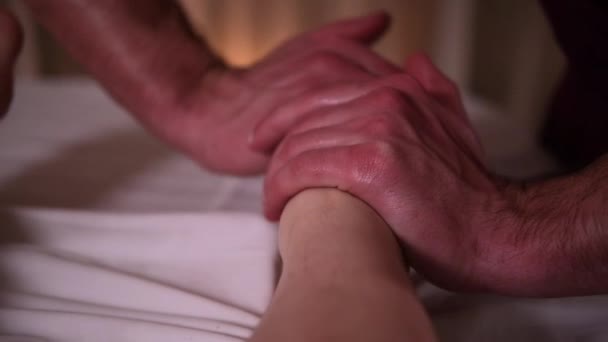 De masseur massages de meisjes been met handen onder romantisch licht — Stockvideo