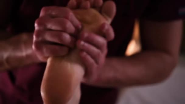 Masér masíruje dívky chodidly s rukama pod romantickým světlem — Stock video